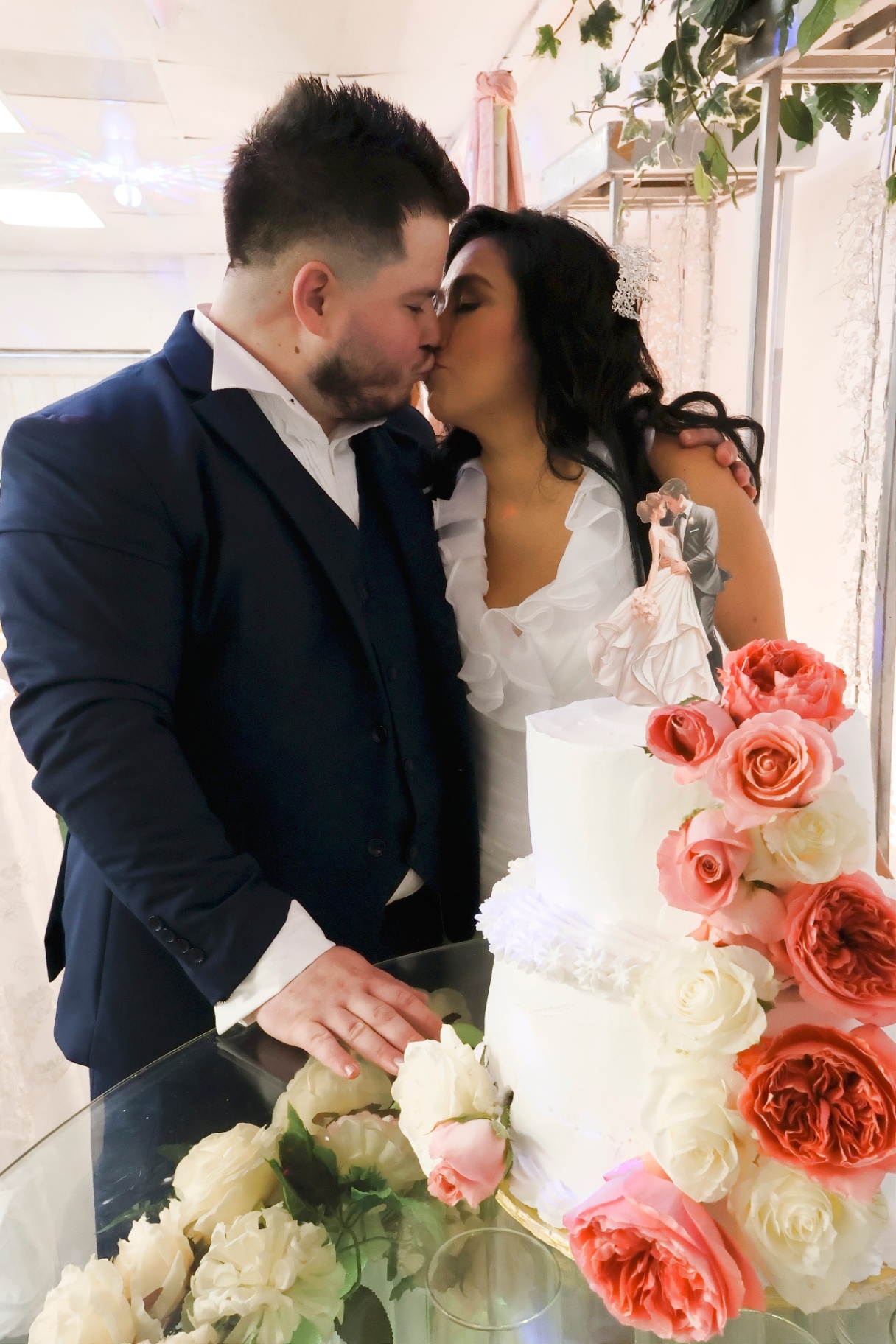 Bride and groom sharing a kiss beside the wedding cake