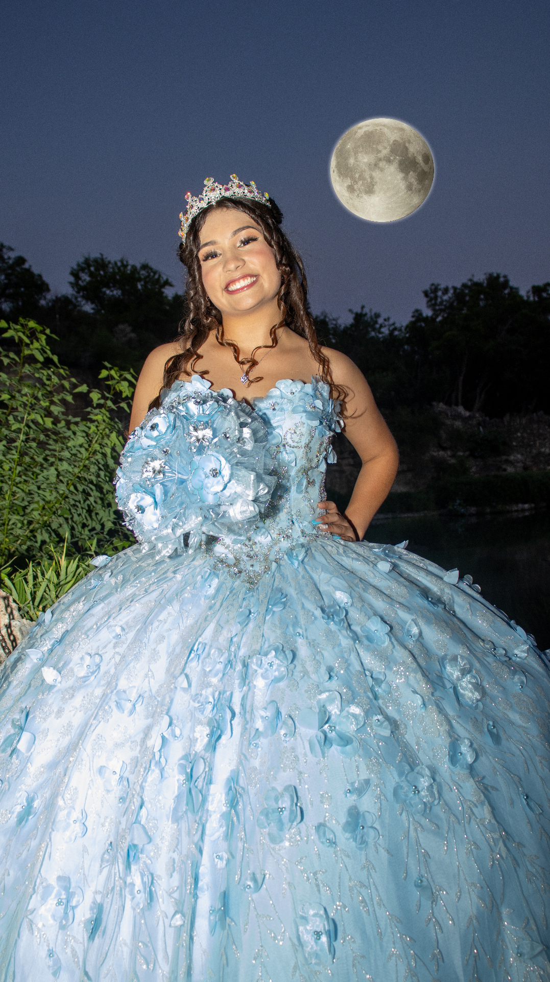 Quinceañera in blue gown under a full moon