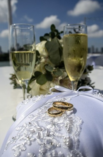 Wedding rings on a lace pillow with champagne flutes and bouquet