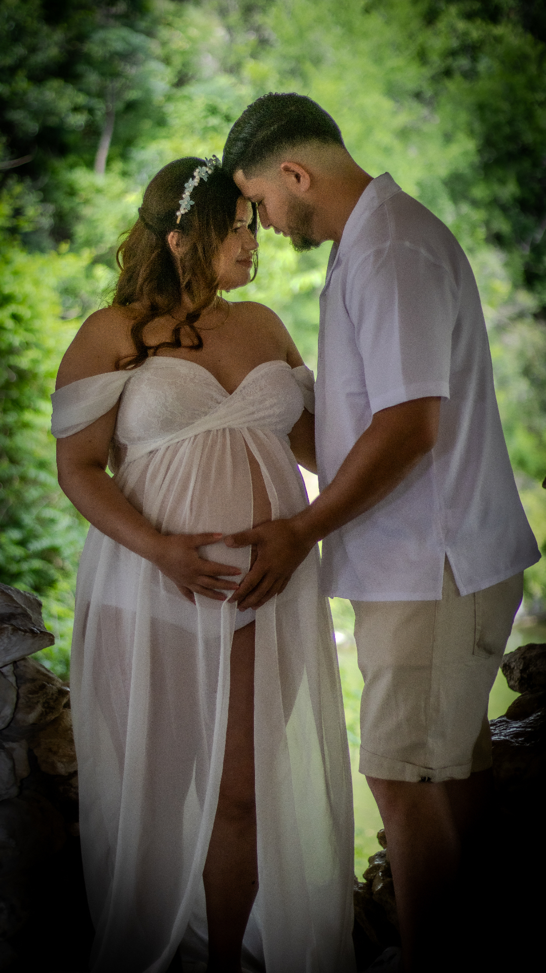 Expecting couple embracing forehead-to-forehead in the woods